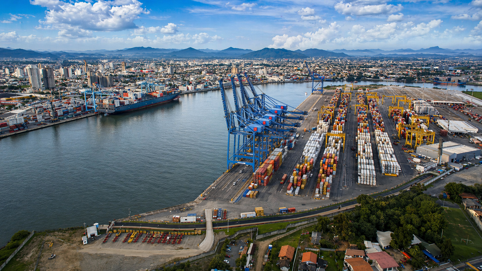 Vista aérea do Porto de Itajaí com guindastes e contêineres empilhados ao longo do rio Itajaí-Açu